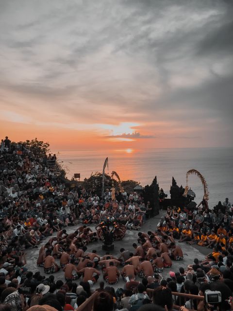 Kecakdans vid Uluwatu-templet i solnedgången, med en ring av barbröstade män kring en fackla och publik på läktarna runt om