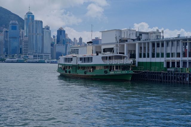 En grönvit Star Ferry-färja vid piren i Tsim Sha Tsui med Hongkongöns skyskrapor bakom
