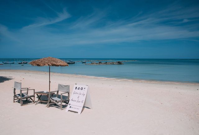 Solstolar och parasoll på en tom strand på Koh Samui